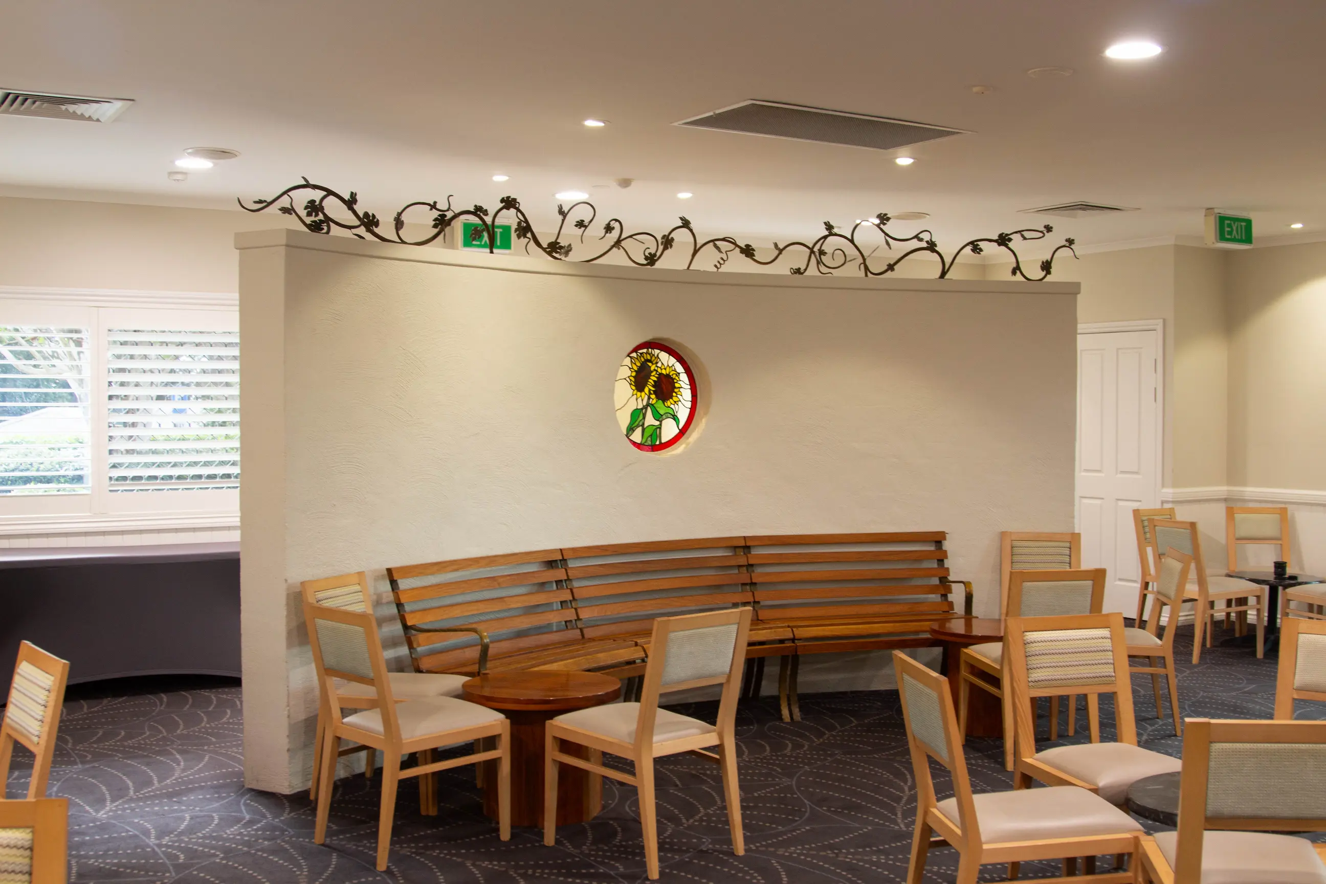Curved seating area with wooden benches, chairs, and decorative wall molding.