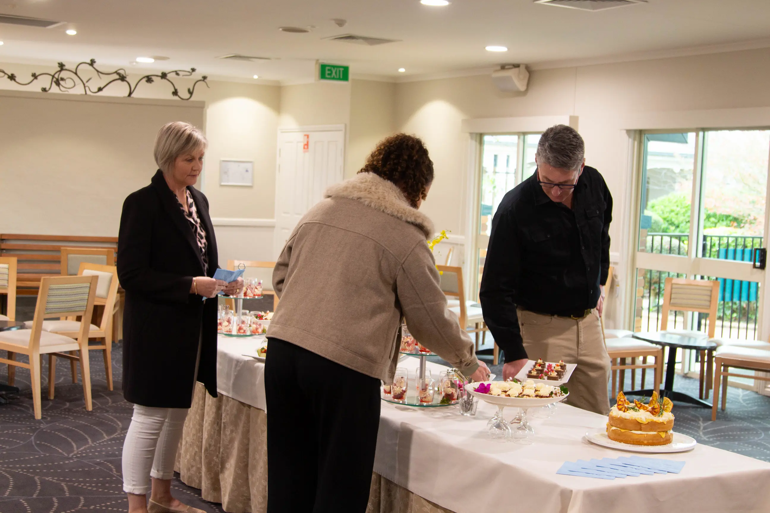 Guests helping themselves to food at a buffet table set up inside a function room.