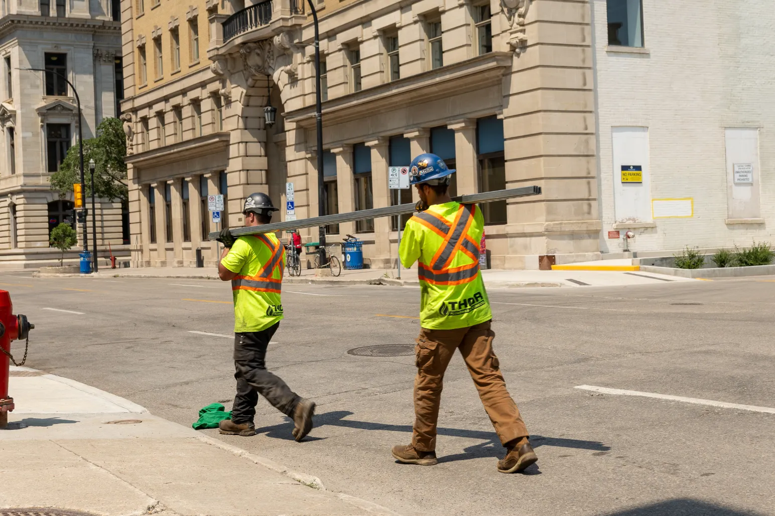 Thor Plumbing & Heating crew carrying steel pipe downtown urban project