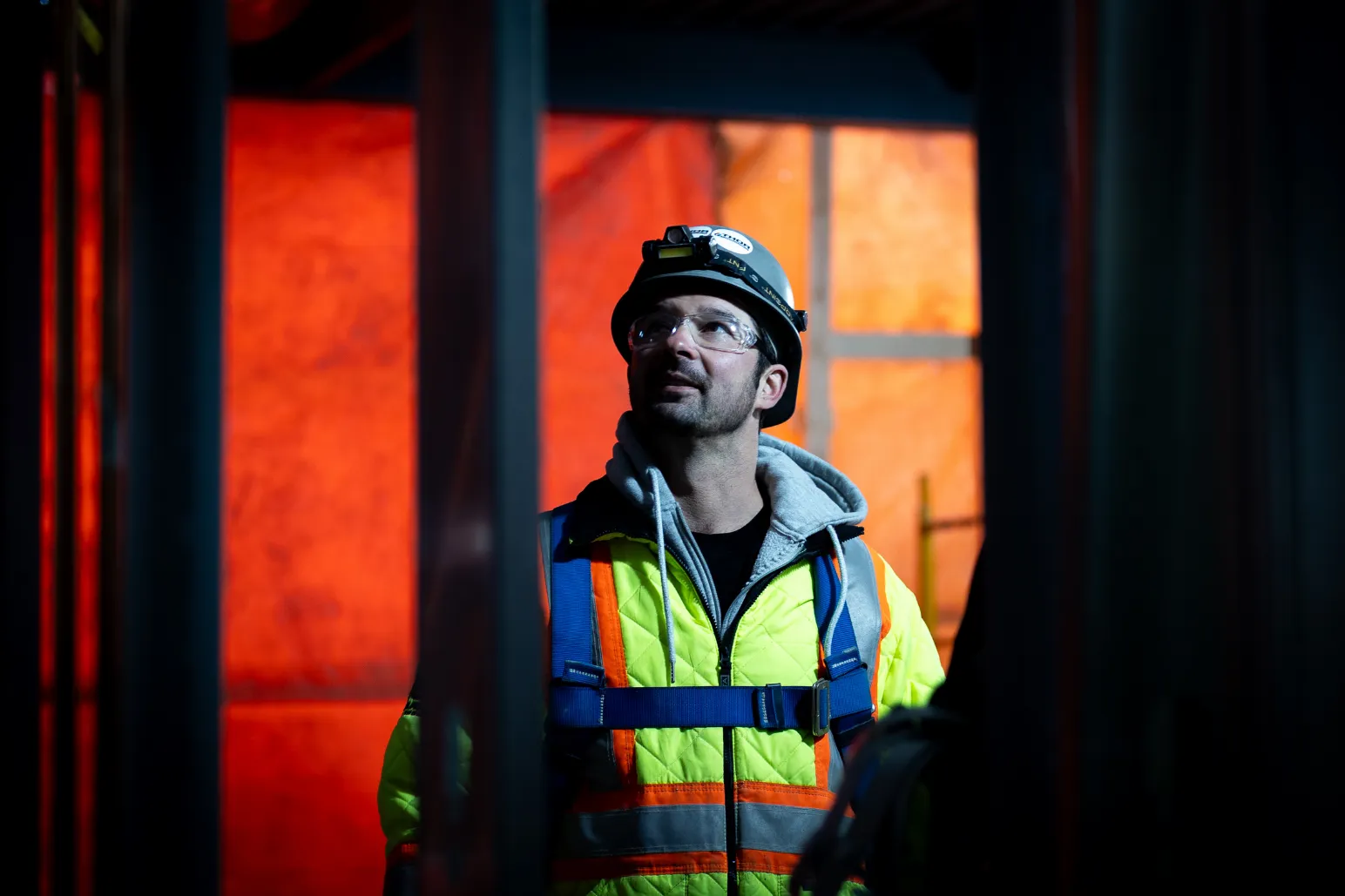 Construction worker silhouetted against orange glow during evening work