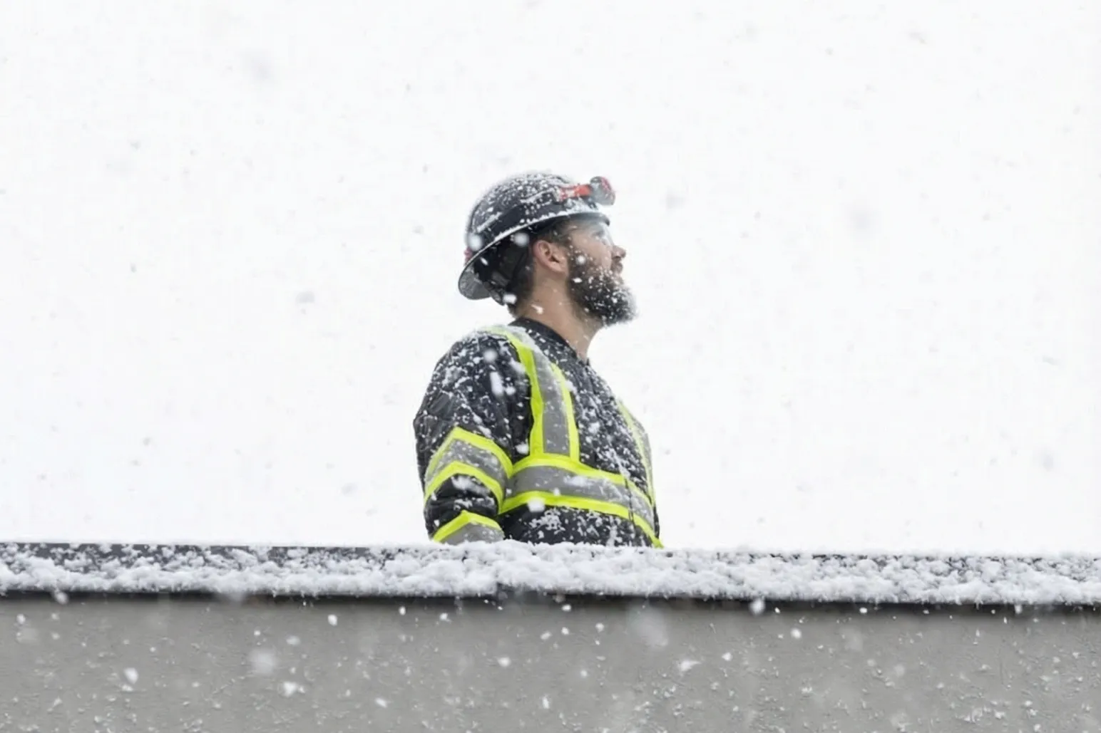 Construction worker on rooftop during heavy snowfall in winter conditions