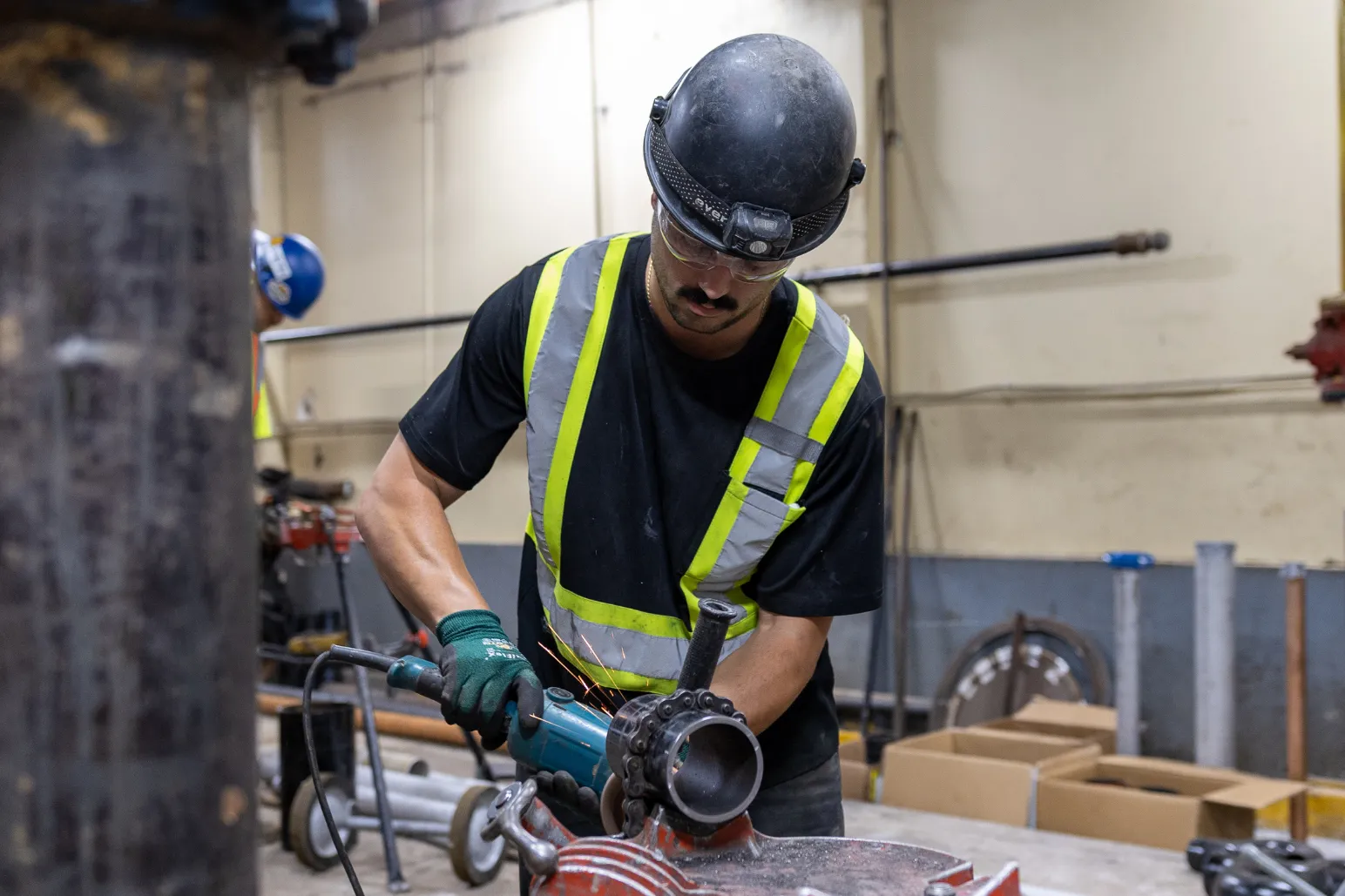 Construction worker using angle grinder cutting metal in workshop