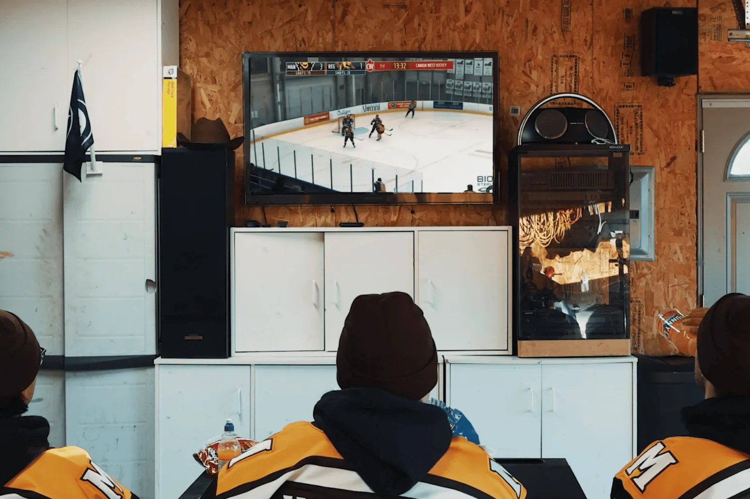 University of Manitoba Bisons hockey players watching game on television in garage