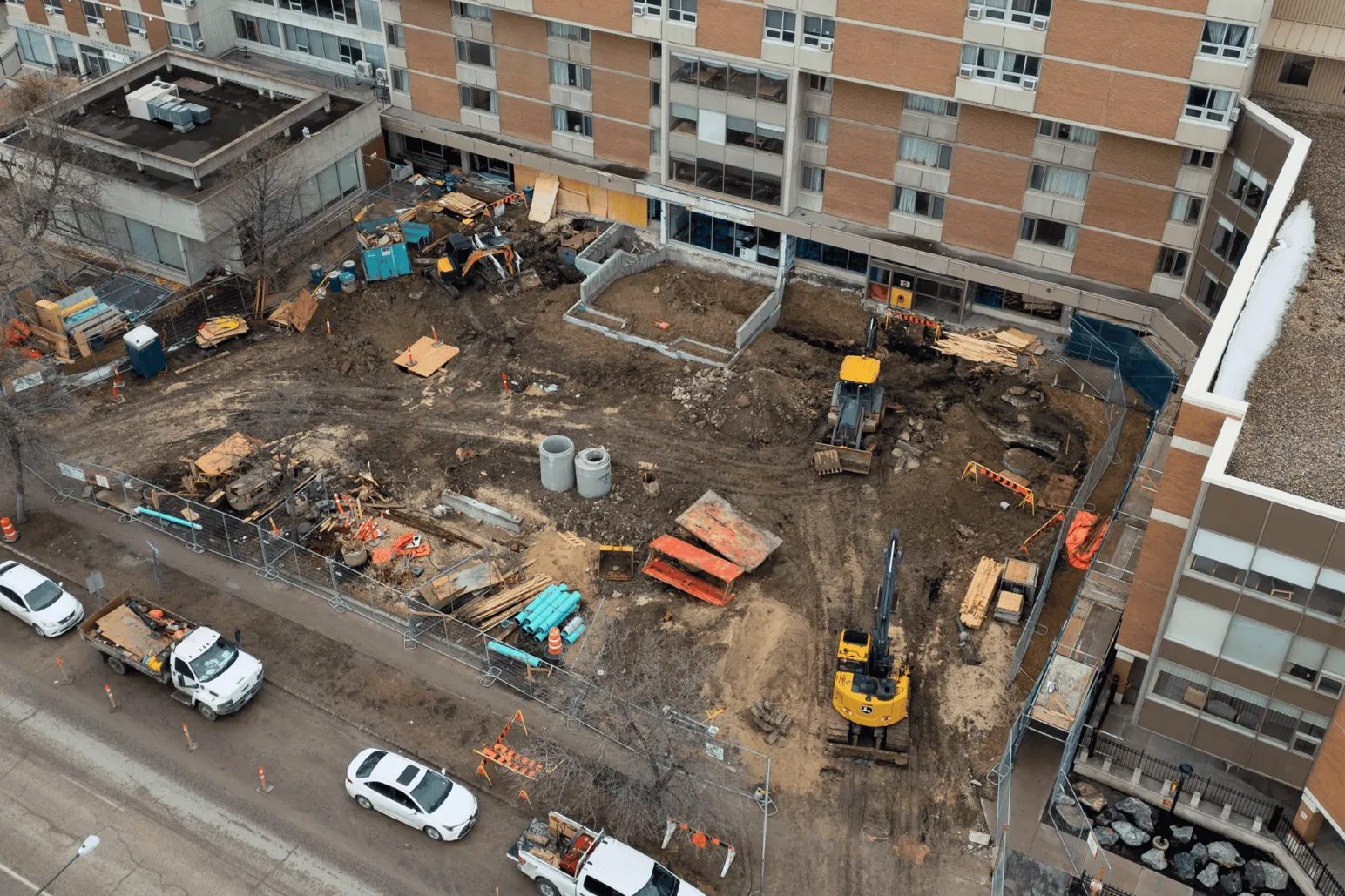 Aerial view of excavation and construction site between existing buildings