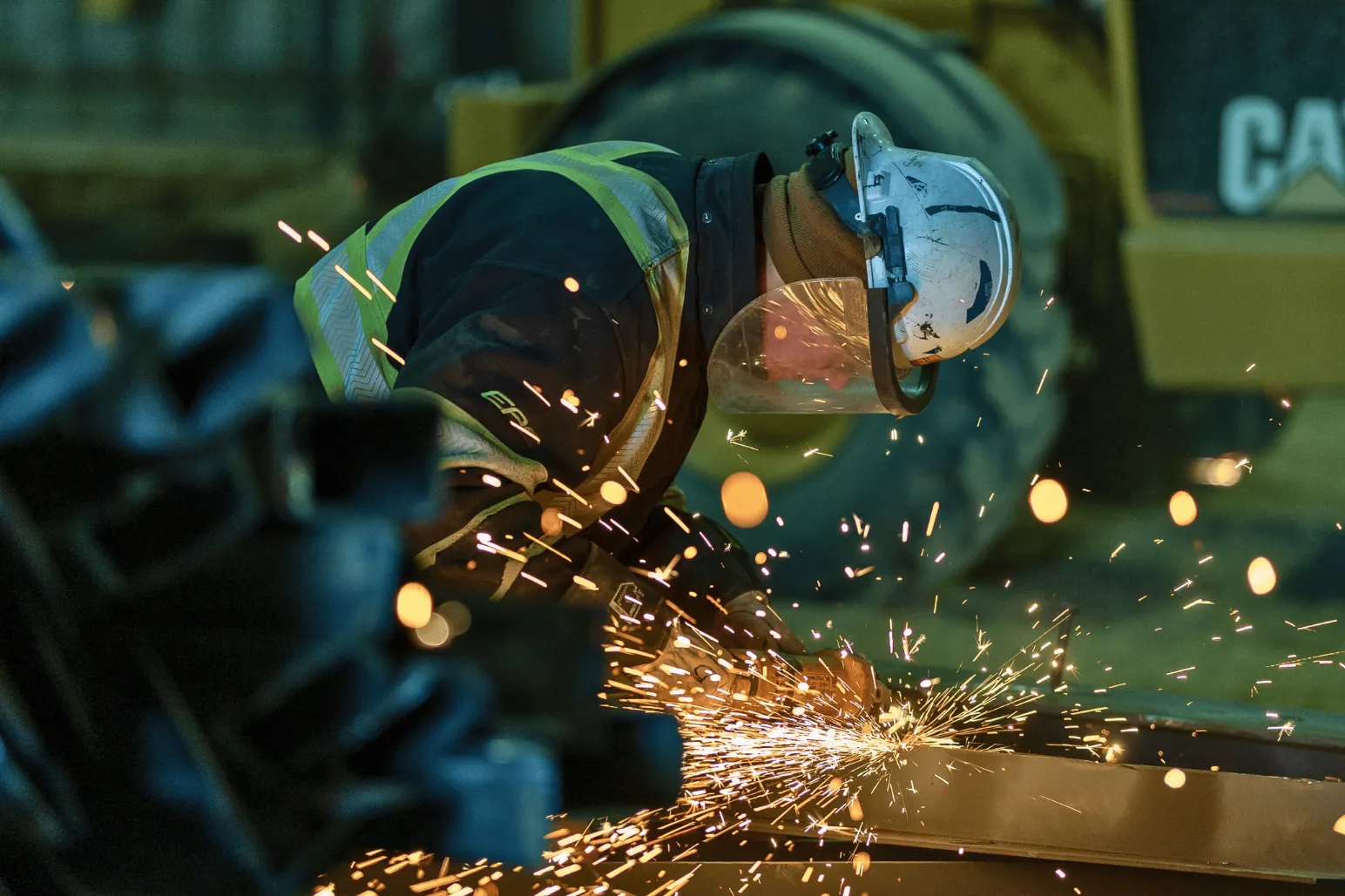 Construction worker using angle grinder creating sparks on metal fabrication
