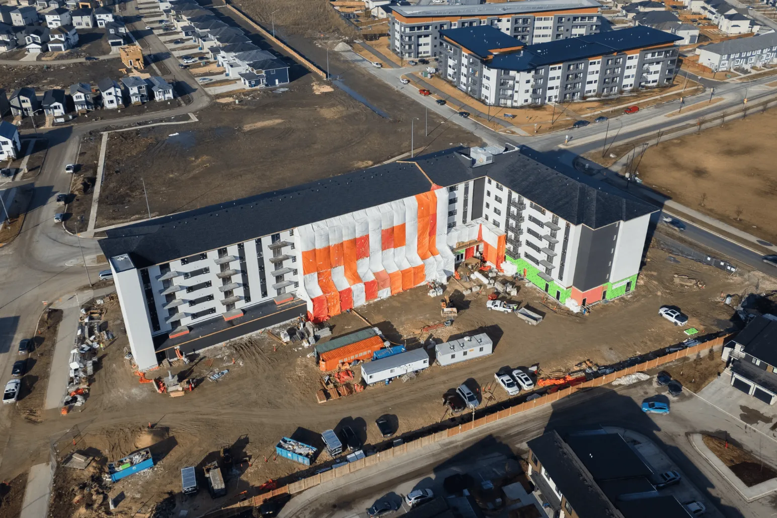 Multi-story residential building under construction with orange accent panels aerial view