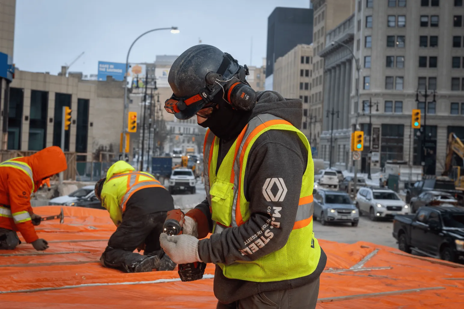 Construction worker wearing respirator mask using power tool at Portage and Main