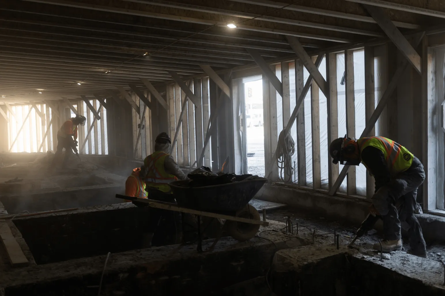Construction workers using wheelbarrow to remove debris from underground tunnel