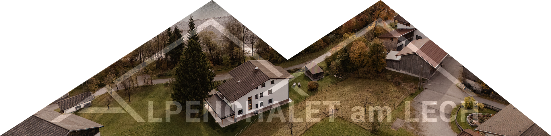 Aerial view of a countryside chalet surrounded by green lawns, trees and paved roads in an autumn setting.