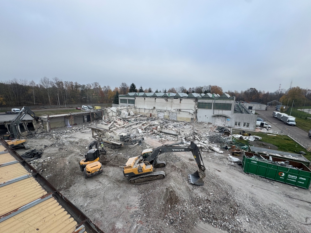 Construction site with heavy machinery demolishing a building and rubble piled around the area.