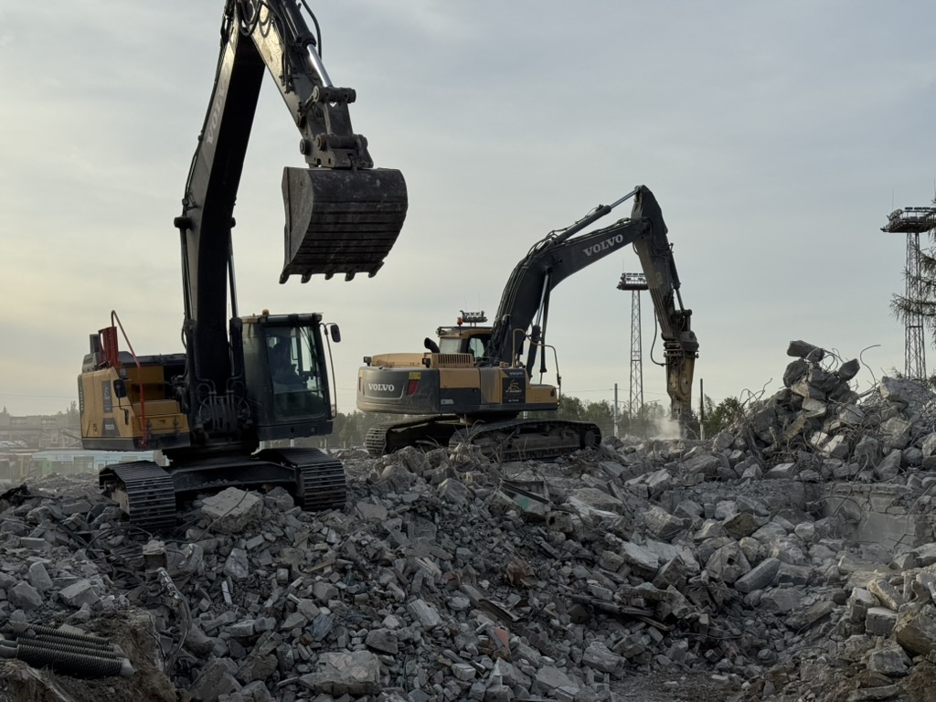 Two Volvo excavators working amid large piles of rubble at a demolition site.