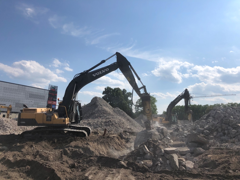 Two Volvo excavators breaking concrete and moving rubble at a sunny construction demolition site.