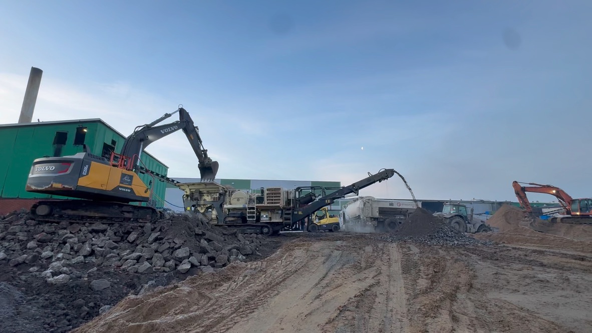 Excavators and machinery working on a rocky construction site under blue sky at dusk.