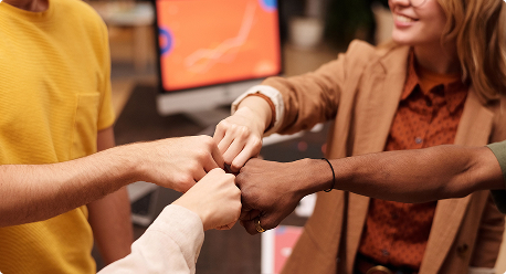 Quatre personnes font un fist bump avec des mains jointes au centre.