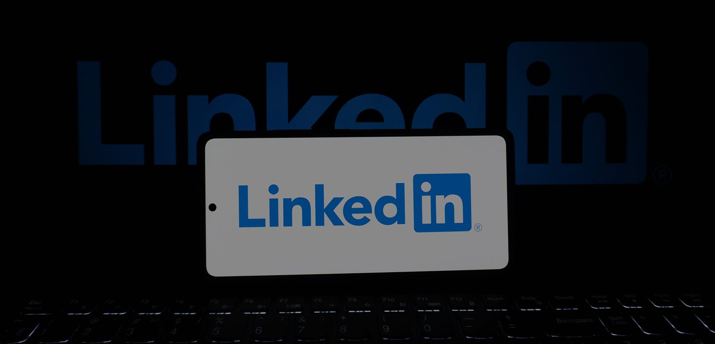 Logo LinkedIn affiché sur un écran blanc et un clavier en dessous dans l'obscurité.