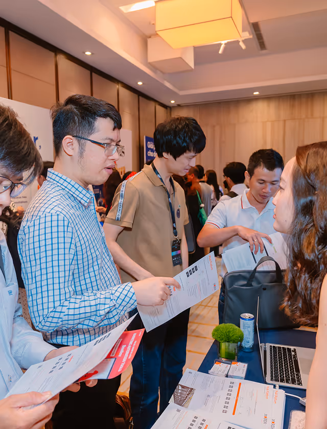 People reviewing documents and talking across a table with a laptop and brochures in a conference setting.