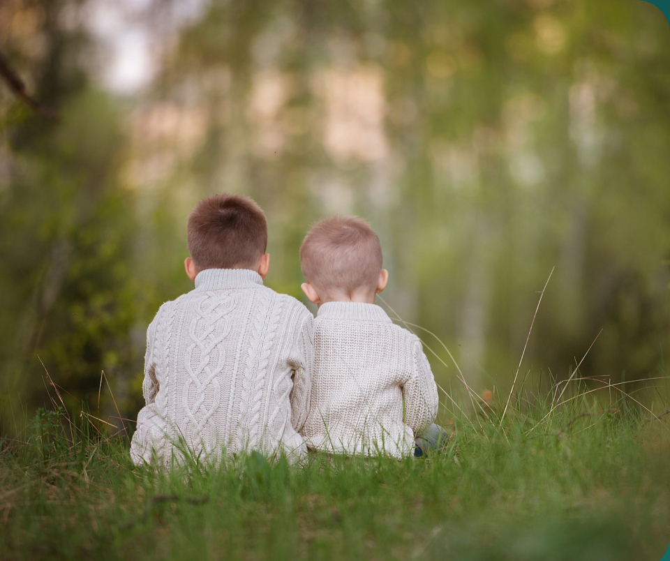 Two children sitting together in a field