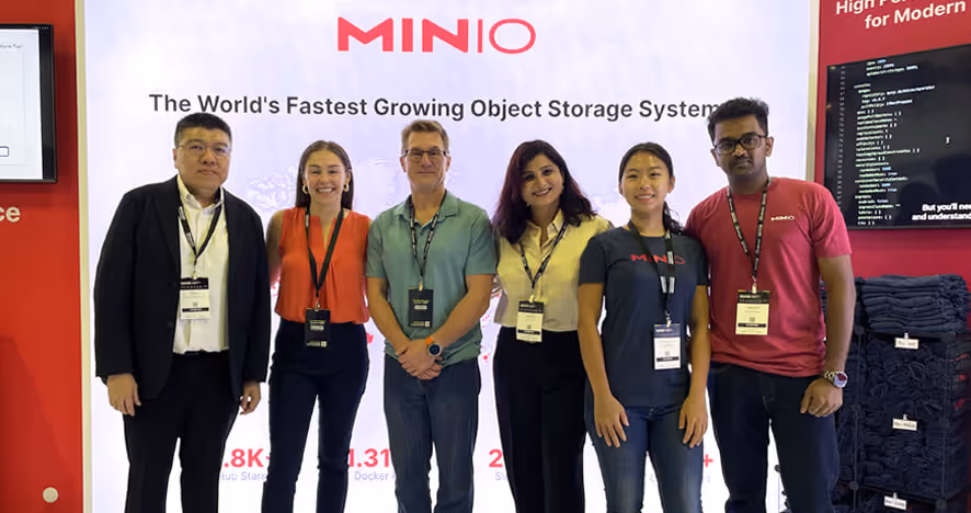 MINIO team standing together at conference with object storage system banner