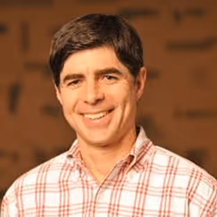 Smiling man in red and white checkered shirt against wooden background