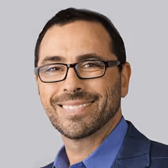 Smiling professional in glasses and blue suit against neutral background