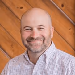 Smiling bald man in checkered shirt against wooden diagonal background