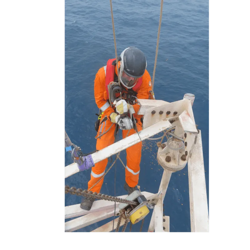 Rope-access technician suspended while cutting flare tower pieces, preparing for safe lifting to deck level during decommissioning.