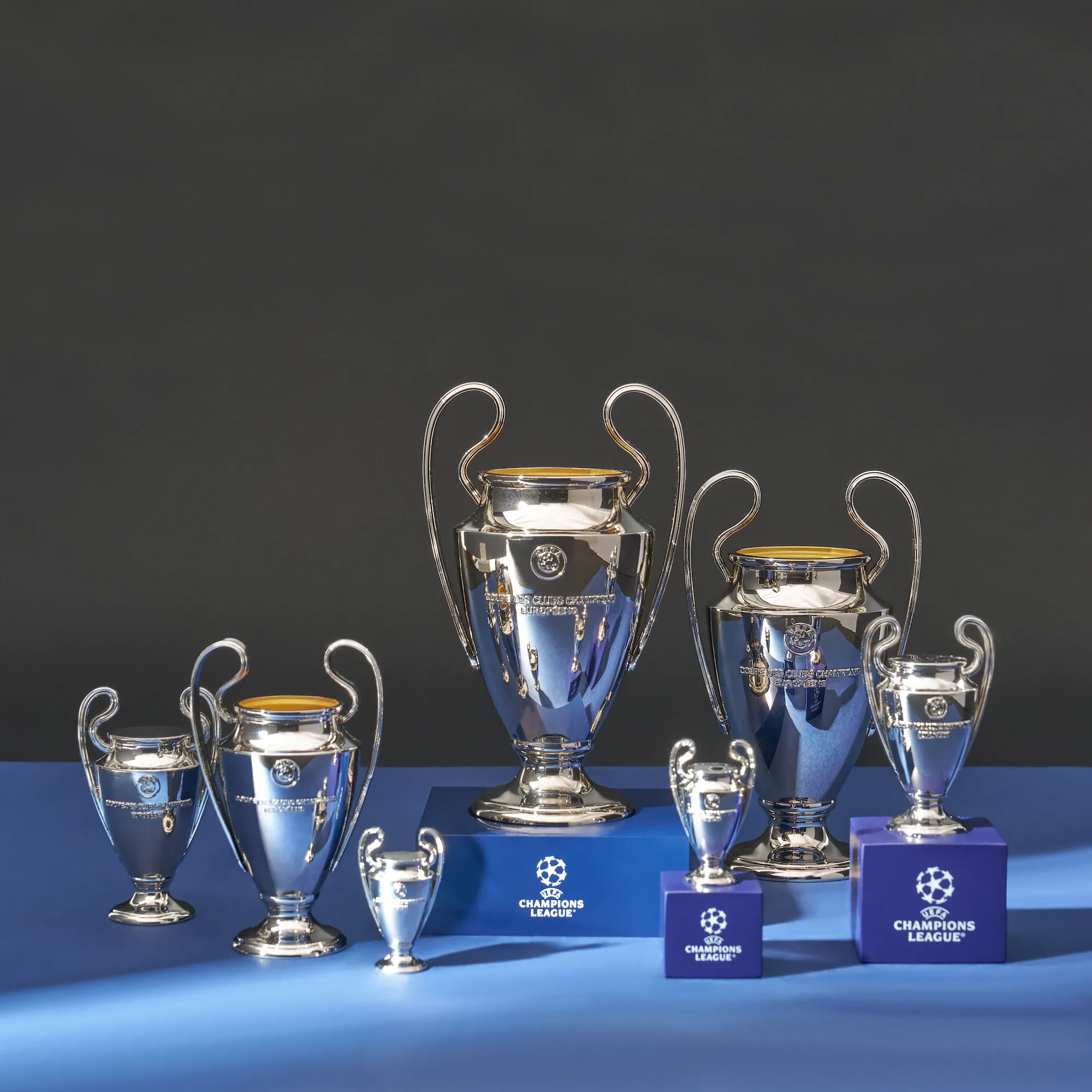Offizielle UEFA Champions League Trophäen-Repliken in 6 verschiedenen Größen auf blauem Hintergrund