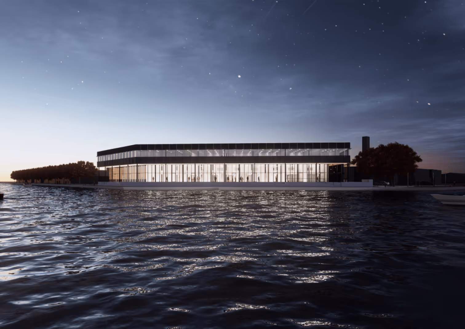 Modern glass building illuminated at dusk beside a body of water with reflections and silhouetted trees in the background.