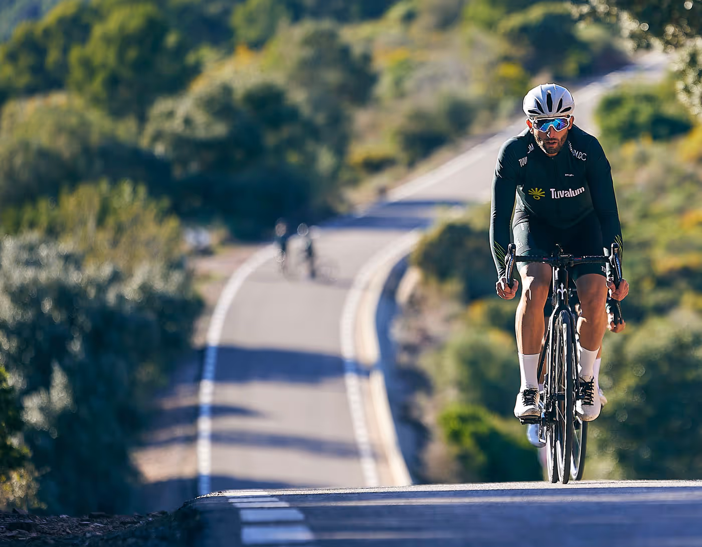 hero image of cyclists riding up a hill