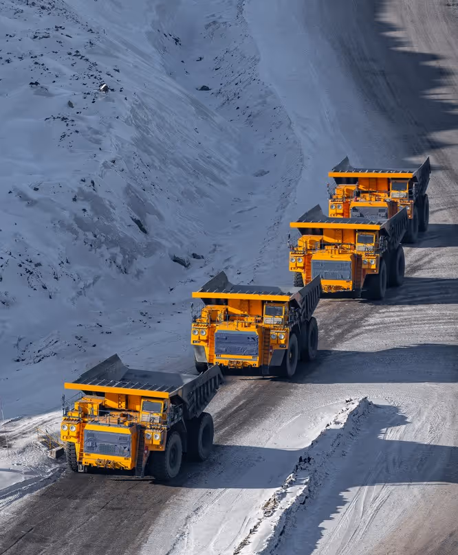Yellow mining dump trucks in convoy at open pit mine for heavy hauling and industrial transportation services
