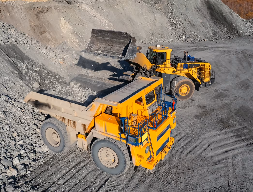 Aerial view of commercial mining operations with wheel loader filling dump truck at industrial quarry site