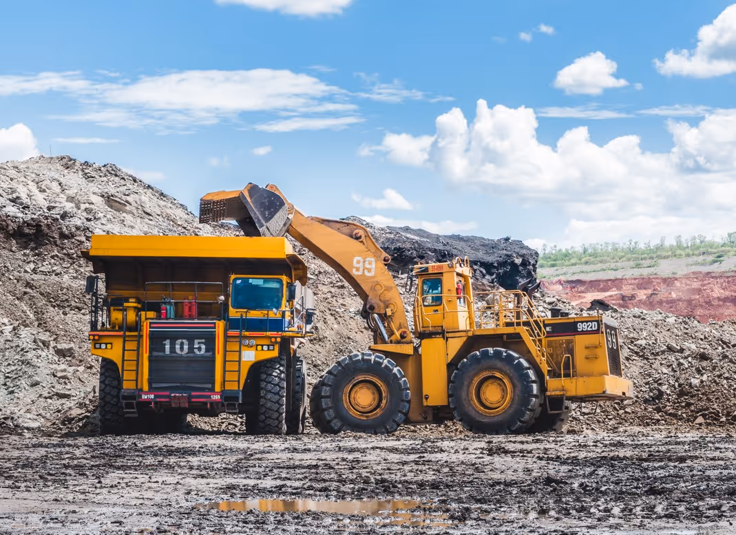 Commercial wheel loader loading haul truck at industrial mining site for heavy equipment logistics and material handling