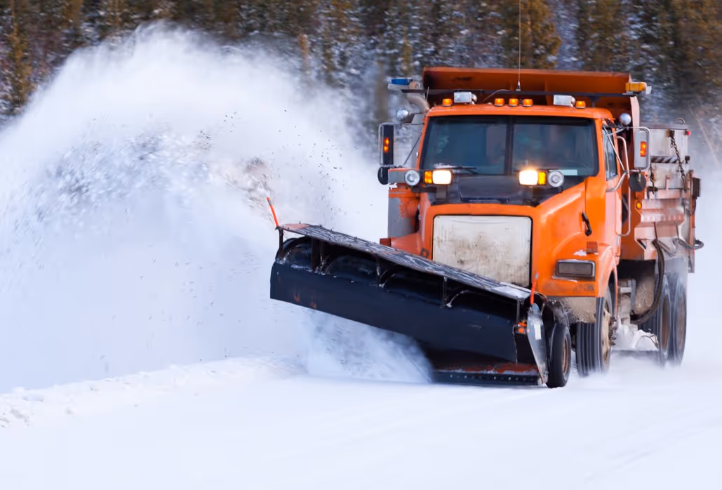 Commercial snow plow truck clearing heavy snow for industrial winter maintenance services