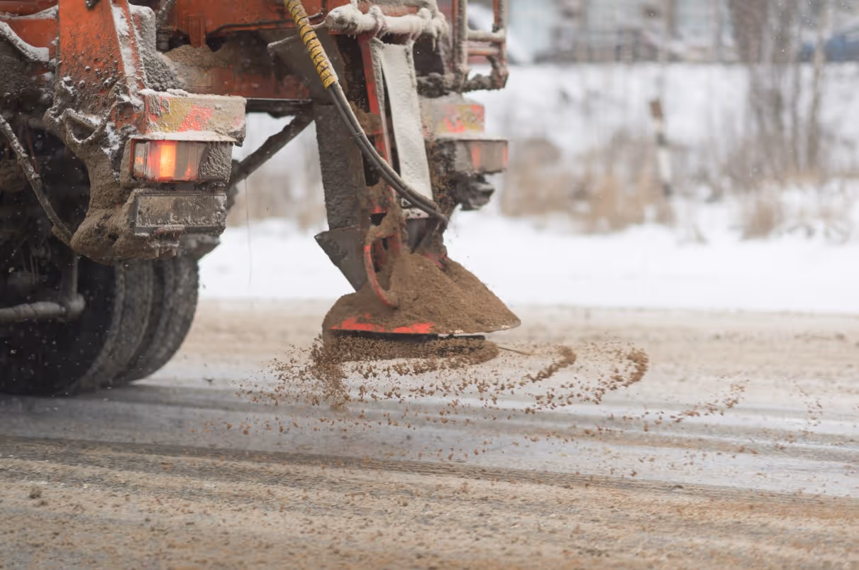 Salt spreader applying road salt for commercial winter ice control and maintenance services