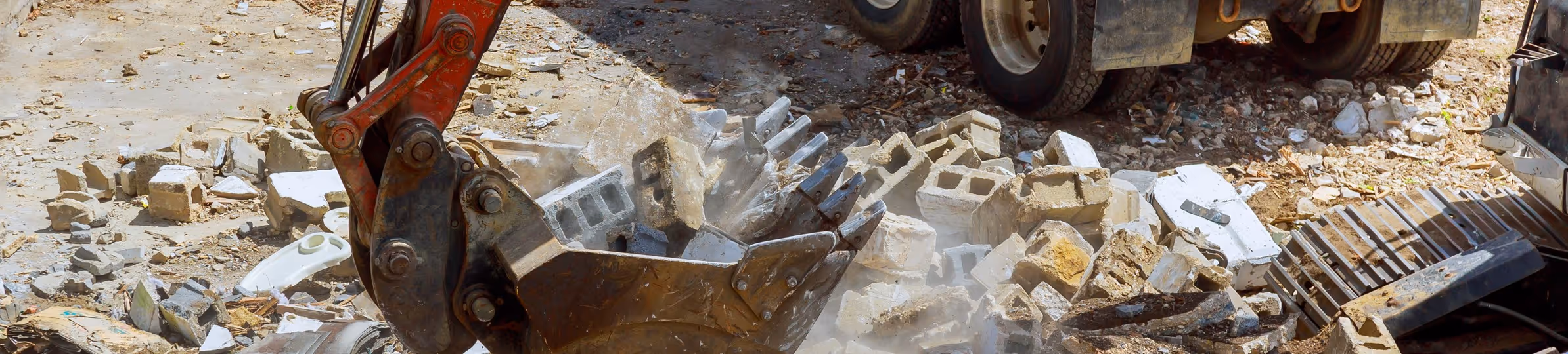 Excavator bucket filled with broken concrete blocks for commercial C&D debris removal services