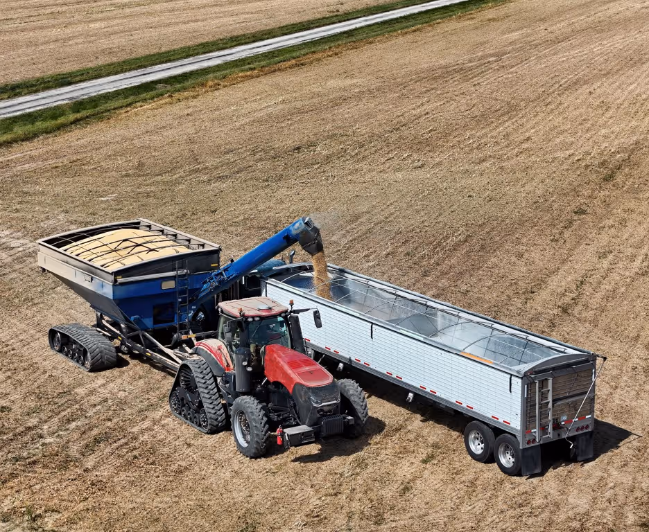 Aerial view of tractor loading soybeans into grain trailer for commercial agricultural hauling services