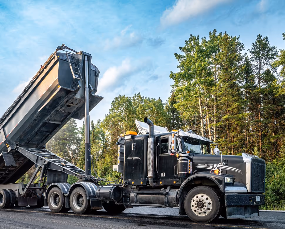 End dump truck with raised bed in forest area for road maintenance material transport services
