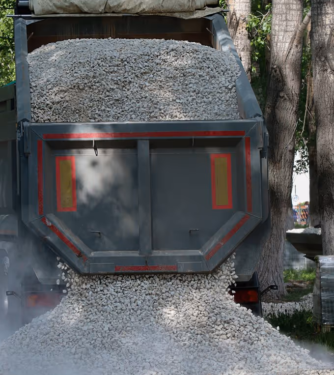 End dump trailer discharging pea gravel through gates for road material delivery services