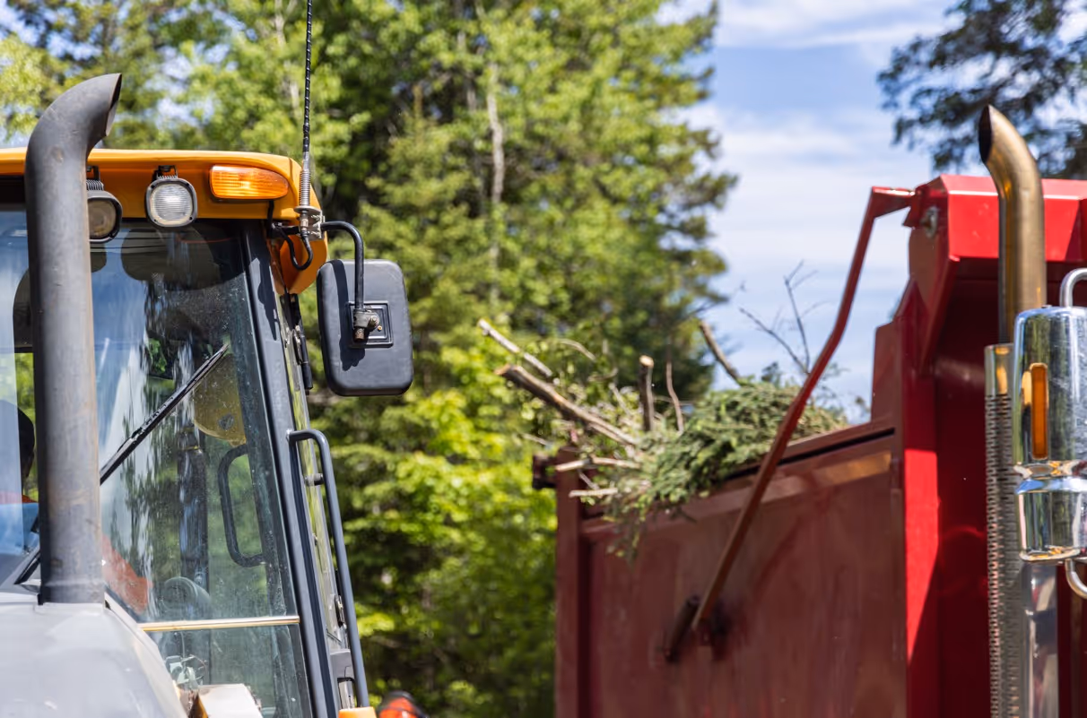 Red commercial dump truck with landscaping debris for green waste transport