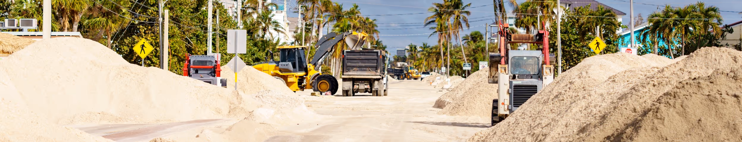 Emergency sand placement on street with trucks and equipment for hurricane response