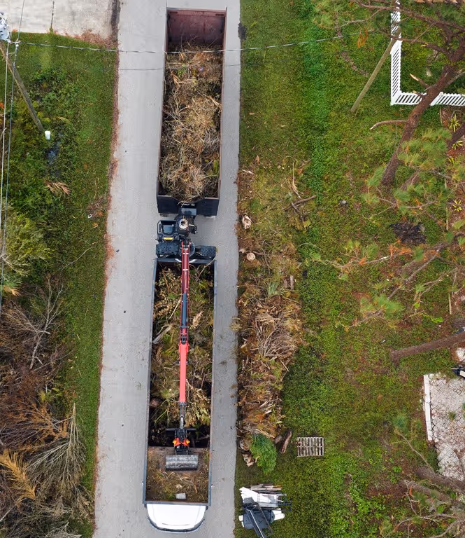 Aerial view of grapple truck removing storm debris from street for emergency hauling services
