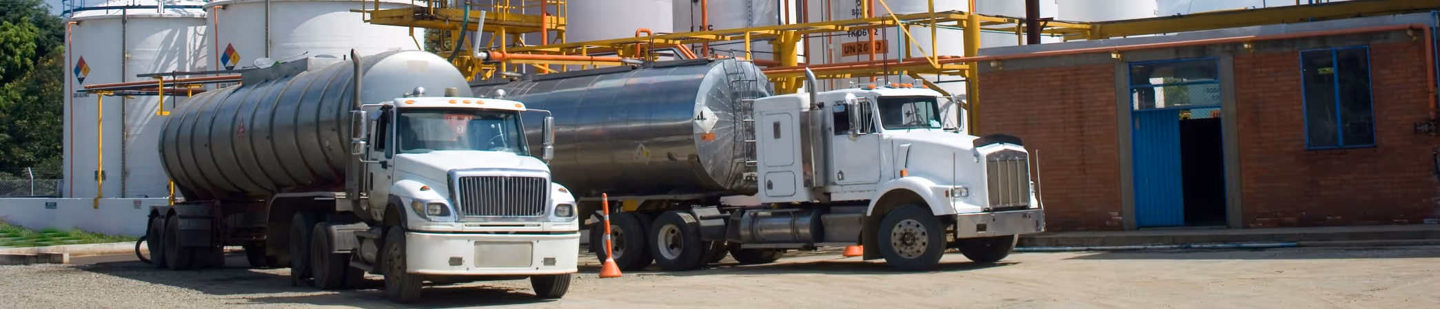 Two tanker trucks at chemical storage facility for bulk liquid loading and transport services