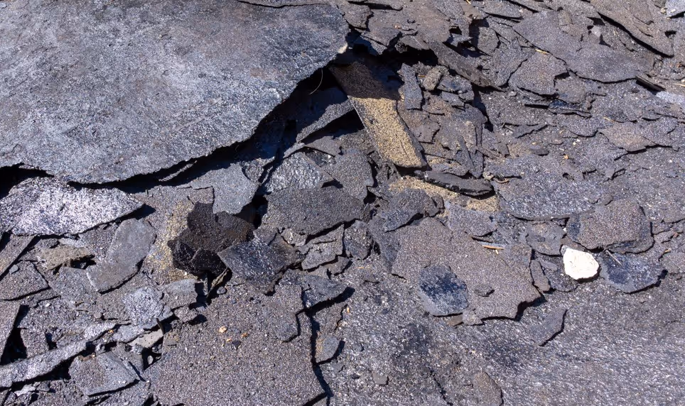 Broken asphalt shingle roofing debris for construction waste removal and recycling transport