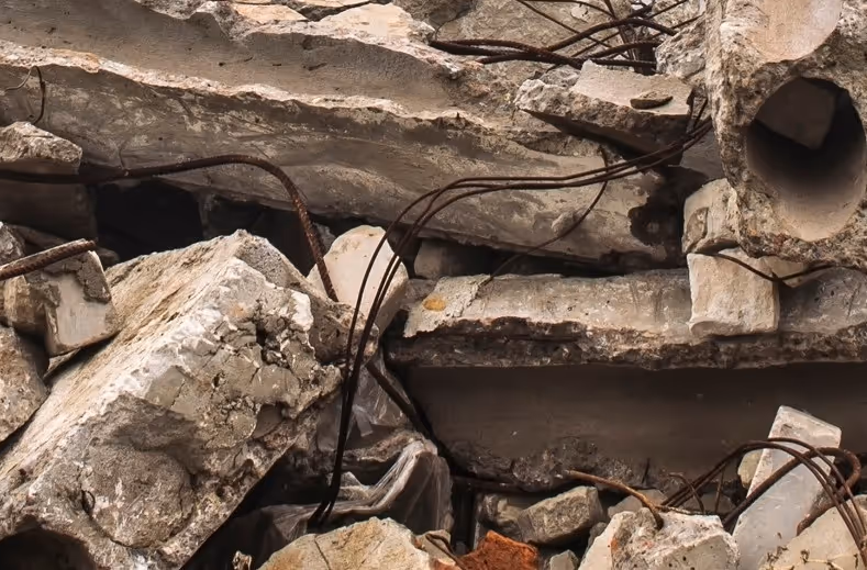 Concrete debris with exposed rebar and cables from industrial facility requiring emergency commercial hauling and disposal