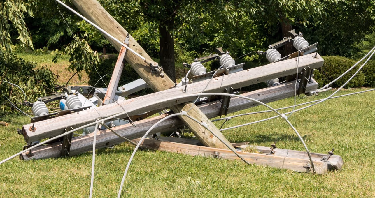 Fallen power lines and utility poles from infrastructure failure requiring emergency commercial hauling and utility cleanup