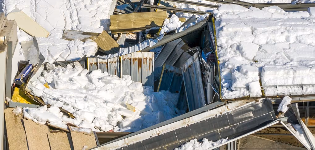 Snow-covered building collapse and structural debris from winter storm requiring emergency commercial hauling and snow removal