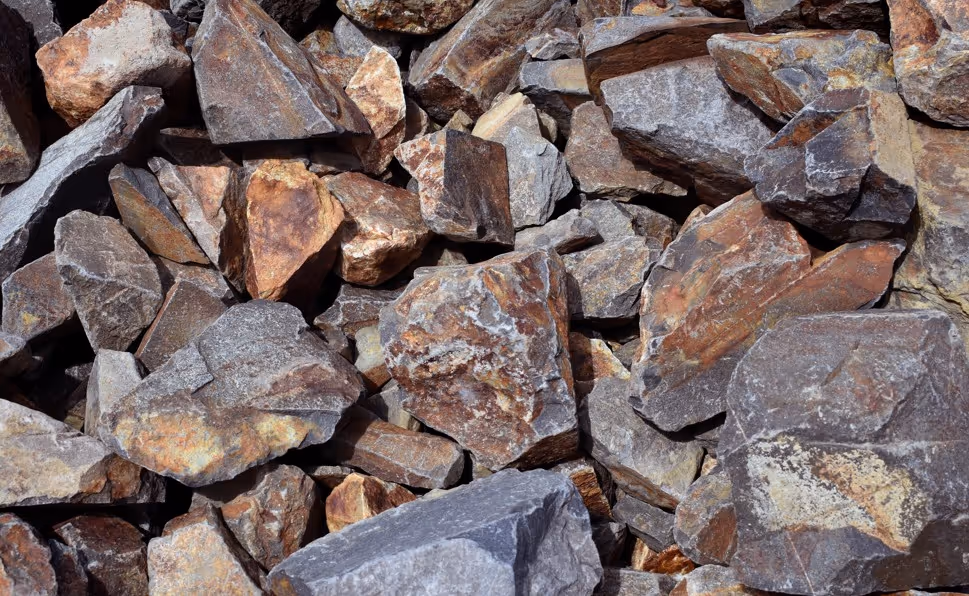 Broken rock and stone fragments from rock excavation operations requiring specialized heavy equipment and hauling