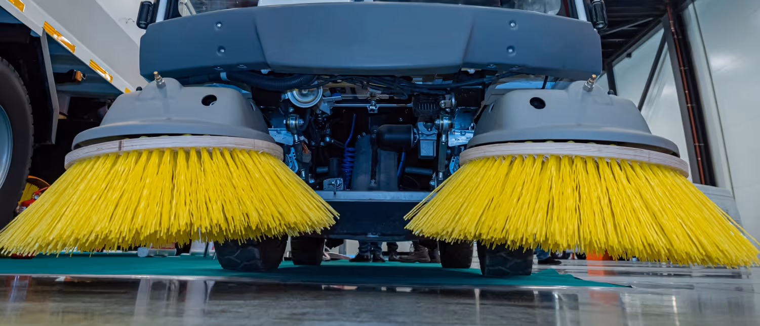 Industrial floor scrubber machine with rotating brushes for commercial cleaning requiring heavy equipment hauling services