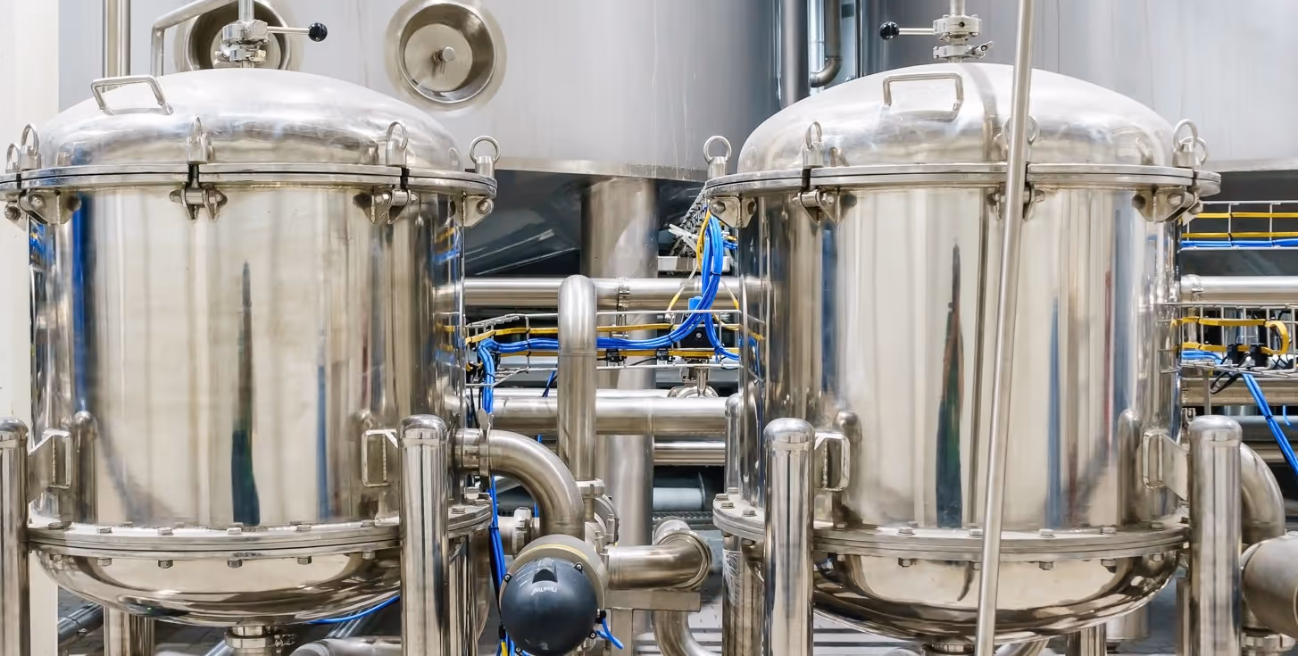 Stainless steel processing tanks and industrial brewing equipment requiring specialized manufacturing equipment hauling services