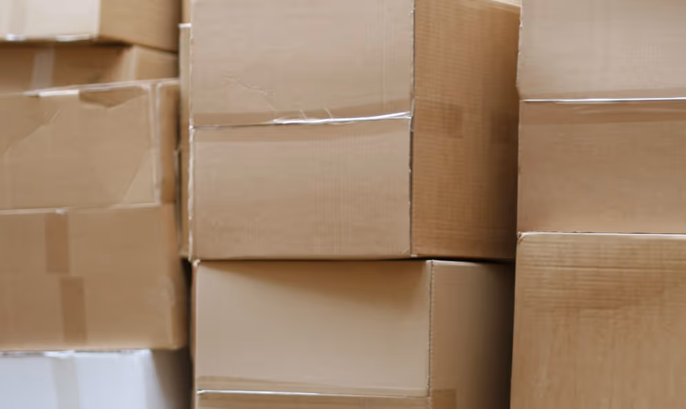 Stacked cardboard boxes and packaging materials from surplus inventory requiring commercial liquidation hauling services